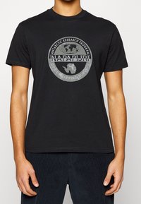 Camiseta de algodón negra con un gráfico circular gris que muestra un globo terráqueo y el texto "Programa de Investigación Antártica" y "Napapijri".