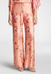 Pantaloni larghi in satin floreale di un morbido pesco con finitura lucida, caratterizzati da motivi di fiori rosa e viola e sottili dettagli drappeggiati.