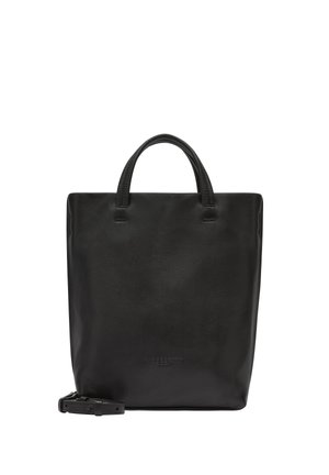 Black leather tote bag with a minimalist design, flat shape, short handles, and an adjustable shoulder strap. Features embossed branding.