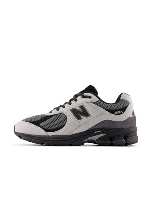 Chaussure de running homme avec tige en mesh noir et gris, empiècements blancs, semelle rembourrée et lacets noirs.