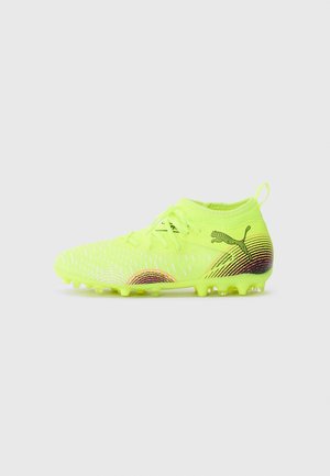 Puma focicipő neon sárga színben, textúrázott felsőrésszel, kontrasztos, sokszínű díszítésekkel, fűzős záródással és tartós tüskés talppal.