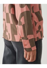 Camicetta a maniche lunghe con un motivo astratto rosa e marrone, con dettaglio a bottone sul polsino e una vestibilità casual. Realizzata in tessuto morbido.