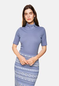 Short-sleeve, mock-neck top in light blue fabric, paired with a patterned skirt featuring alternating horizontal stripes in blue and white.