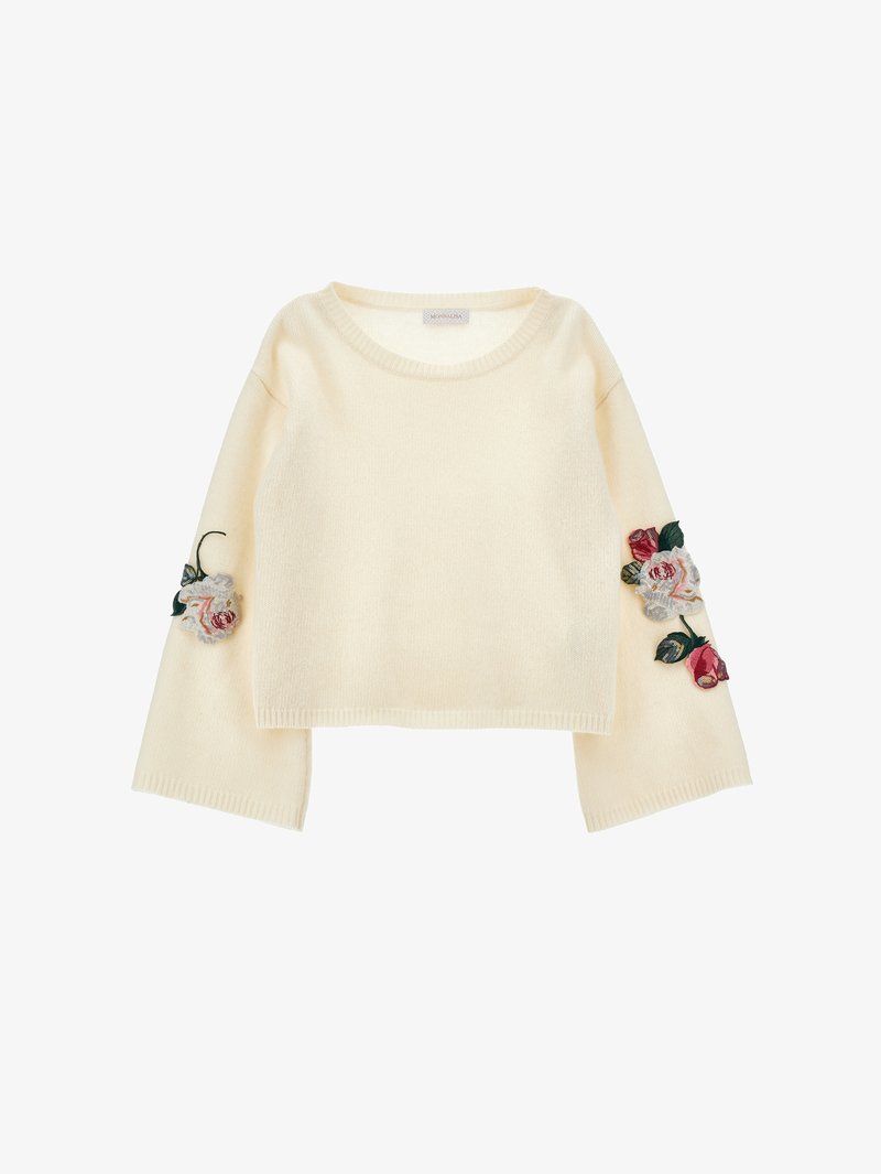 Śmietankowy sweter z okrągłym dekoltem i dzwonowymi rękawami, zdobiony kwiecistym haftem w różowym i czerwonym na rękawach. Miękka faktura.