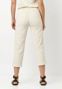 Hellbeige, locker sitzende Cropped-Hosen mit aufgerolltem Saum, zwei Gesäßtaschen und einer glatten Baumwolltextur.