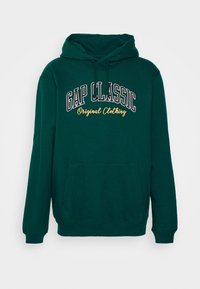 Felpa verde in cotone, con tasca frontale, cappuccio con cordino e testo "GAP CLASSIC" in bianco e giallo.