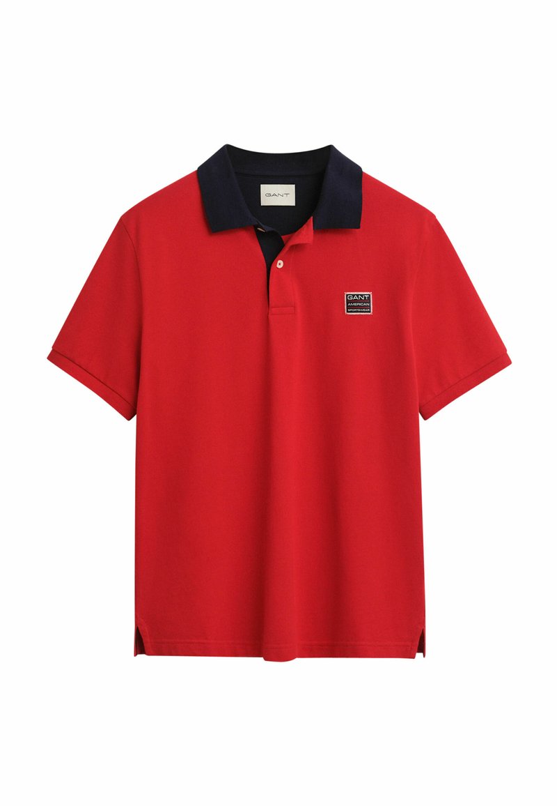 Rotes Poloshirt mit marinefarbener Kragen, kurzen Ärmeln und einem Marken-Logopatch auf der linken Brust. Verfügt über seitliche Schlitze am Saum für zusätzlichen Komfort.