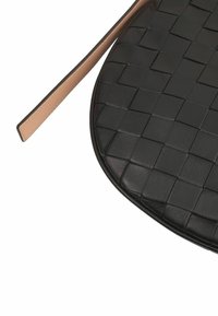 Zwarte geweven leren handtas met een gladde, ronde vorm en een contrasterende lichtbruine schouderband. Heeft een vlakke, gestructureerde oppervlakte.