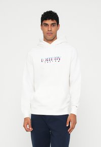 Λευκή hoodie με μπροστινή τσέπη, κουκούλα με κορδόνι και πολύχρωμο λογότυπο "tommy jeans" σε μαλακό, υφασματοποιημένο υλικό.