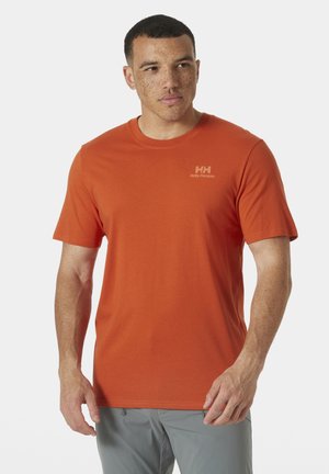 Camiseta de manga corta naranja hecha de una tela suave, con cuello redondo y un pequeño logo en el área del pecho izquierdo. Textura lisa.
