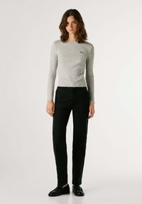 Camisola de manga longa cinza claro com decote redondo, combinada com calças pretas ajustadas e sapatos pretos. Design simples com detalhes mínimos.
