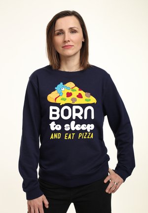 Marineblaues Sweatshirt mit einem Cartoon-Pizzastück, das Herzen, Pilze und einen blauen Bären zeigt. Text: "GEBOREN zum Schlafen UND PIZZA essen."