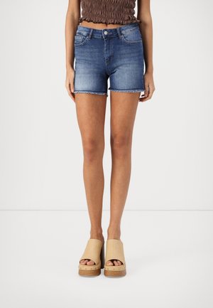 Shorts en denim bleu foncé, taille mi-haute avec un ourlet effiloché. Assortis à des sandales à plateforme beige avec des talons en bois et un design ouvert. 