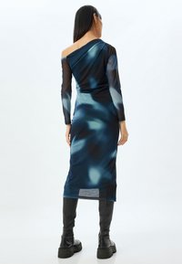 Robe élégante, décolletée sur les épaules, avec un motif abstrait bleu. Fabriquée en tissu lisse, elle possède des manches longues et une silhouette ajustée.