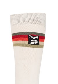 Kniehoge sokken in crème met meerkleurige horizontale strepen (rood, groen) en een zwart logo-label nabij de bovenkant. Gestructureerde geribbelde rand.