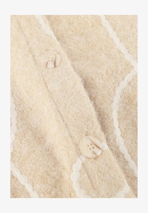 Beige gebreide cardigan met een zachte, gestructureerde wolstof, decoratieve witte piping en ronde crèmekleurige knopen met twee gaten.