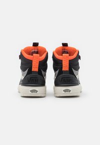 Vysoké tenisky Vans v černé barvě s šedými akcenty, oranžovým fleecovým podšíváním a značkovými poutky, s texturovanými podrážkami a polstrovanými límci.