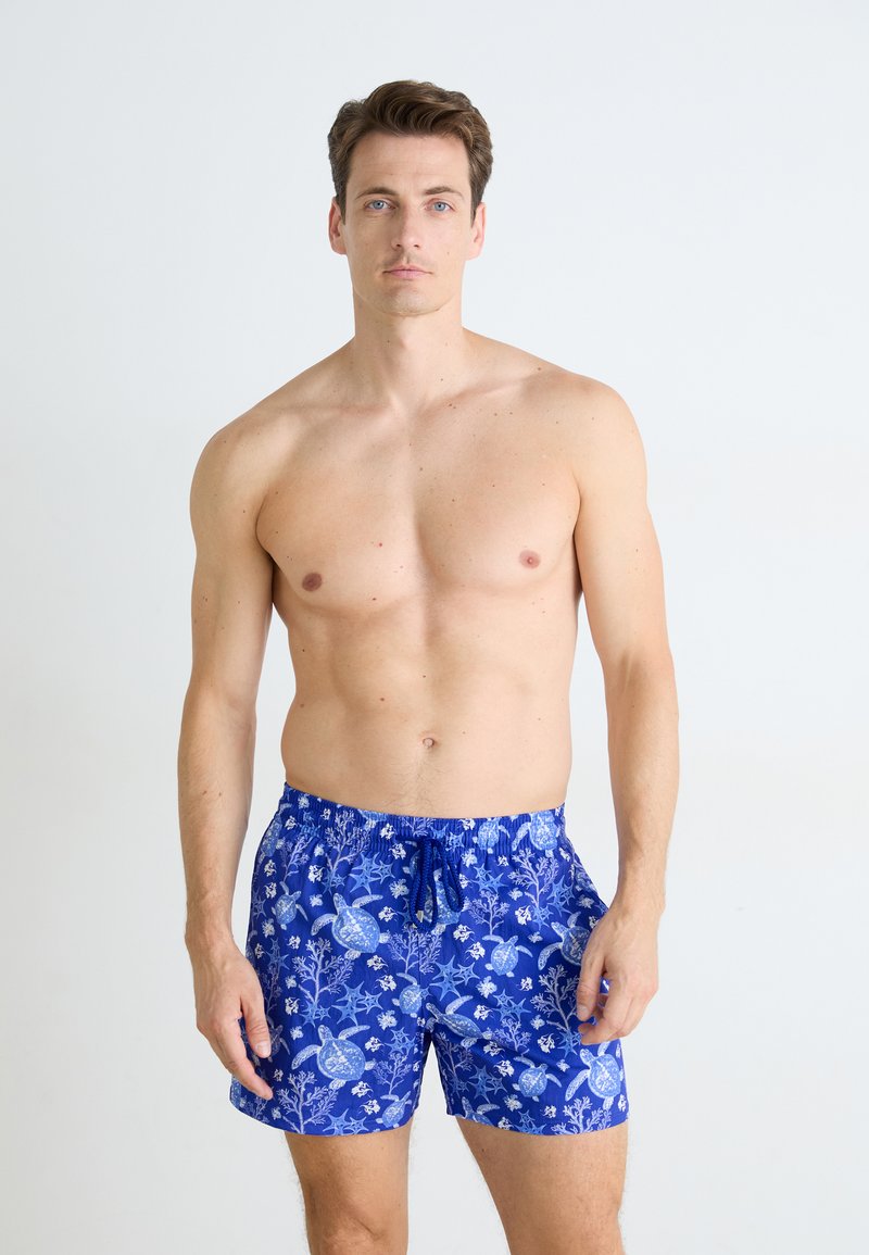 Costum de baie albastru cu un model floral și cu țestoase, talie elastică și șnur ajustabil. Fabricat dintr-un material ușor.