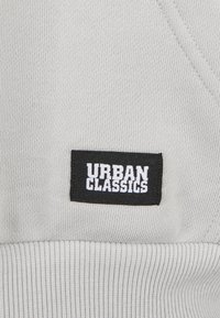 Gray sweatshirt fabric with ribbed texture; features a black rectangular tag with "URBAN CLASSICS" in white lettering.