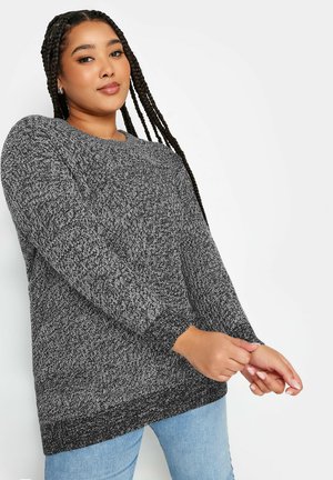 Suéter de punto negro y blanco de gran tamaño con mangas largas y puños acanalados, que presenta un patrón texturizado y un cuello redondo.