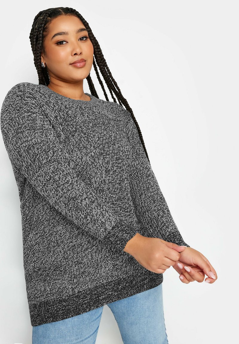 Överdimensionerad svart och vit stickad tröja med långa ärmar och ribbade mudd, med ett strukturerat mönster och rund halsringning.