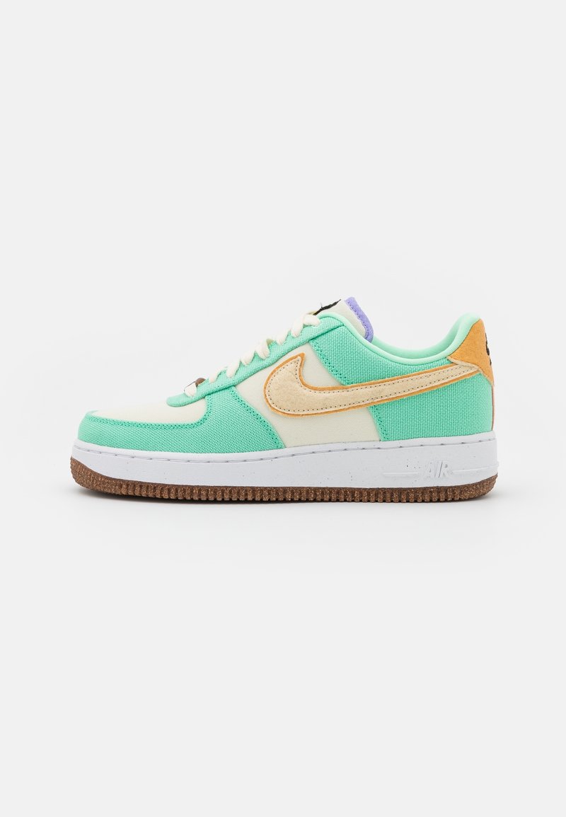 Baskets basses vert menthe et crème avec le logo Nike orange, semelle blanche et semelle extérieure texturée marron, vues de côté.