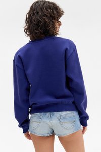Sweatshirt azul marinho com corte oversized, punhos e bainha canelados, combinado com calções de ganga claros com detalhes discretos nos bolsos traseiros.