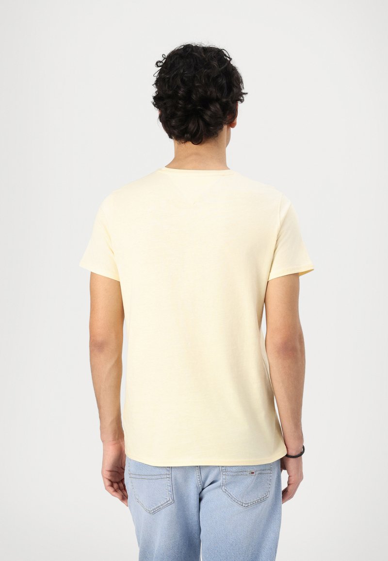 Camiseta de algodón amarilla con mangas cortas, escote redondeado y un corte relajado. La vista trasera muestra una textura suave y un diseño sencillo.