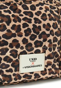 Leopardenmuster Tasche in Beige- und Brauntönen. Mit einem weißen Label, auf dem "UNIO HAMBURG x LES VISIONNAIRES" in schwarzer Schrift steht. Glatte Textur.