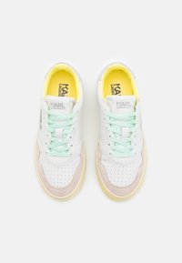 Białe skórzane sneakersy z miętowymi sznurowadłami, żółtą wyściółką, brązowymi zamszowymi akcentami, perforowanym noskiem i detalami z logo na języku.
