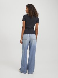 Svart tettsittende t-skjorte med korte ermer i kombinasjon med lyseblå vide jeans. Antrekket har en jevn tekstur og en avslappet design.