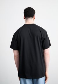 Zwarte katoenen t-shirt met een ronde hals, korte mouwen en een ontspannen pasvorm. Gladde textuur, eenvoudig ontwerp, geen zichtbare patronen of hardware.