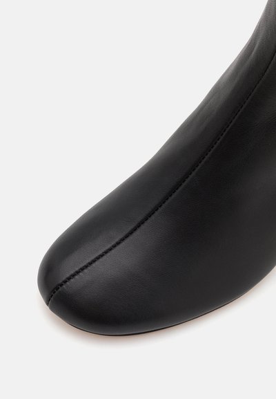 Cizmă neagră din piele cu o textură netedă, vârf ascuțit și cusături subtile pe lateral, evidențiind un design elegant.