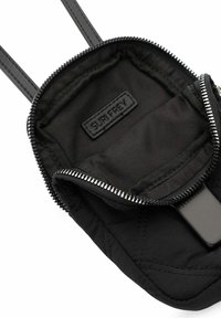 Pochette noire en nylon avec texture matelassée, fermeture éclair et doubles poignées. L'intérieur présente une étiquette et un revêtement lisse. Design compact pour les essentiels.
