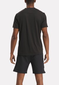 Sort kortærmet t-shirt lavet af bomuld, med en klassisk rund hals og en glat tekstur. Båret med sorte atletiske shorts.