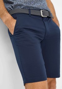 Marineblaue Shorts aus leichtem Stoff, mit klassischer Passform, seitlichen Taschen und einem strukturierten grauen Webgürtel.