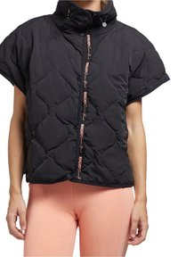 Veste noir matelassée à manches courtes avec col montant, fermeture à boutons et texte logo rose sur le devant, portée avec des leggings pêche.