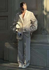 Light beige suit with a blazer and wide-leg trousers, paired with a small cream handbag and sunglasses, showcasing a textured fabric.