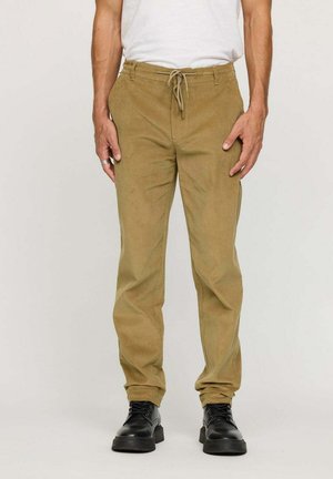 Pantalons en velours côtelé kaki avec taille à cordon, jambes fuselées et deux poches latérales, associés à des chaussures noires à lacets.