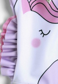 Tessuto bianco con un design di unicorno, caratterizzato da un bordo arricciato viola, accenti rosa, contorni neri e un dettaglio rosa sulle guance.
