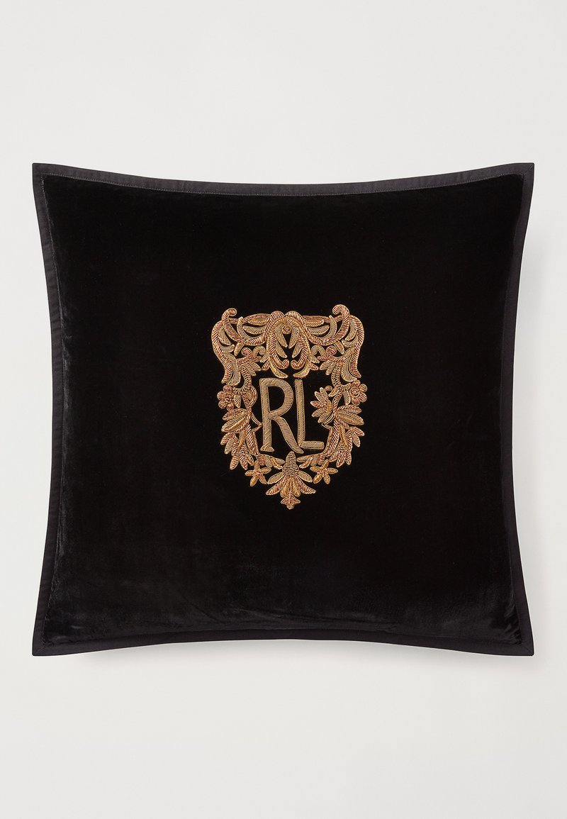 Almofada de veludo preto com um brasão bordado em dourado e bronze, apresentando "RL" e detalhes florais intricados. Textura suave e forma retangular.