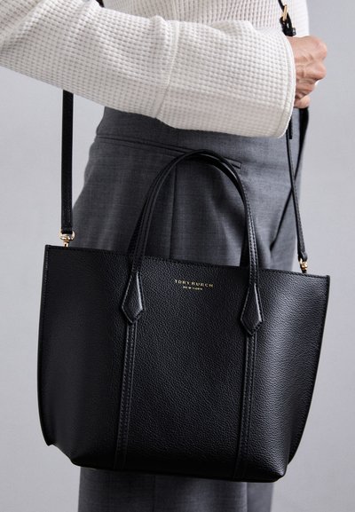 Sac à main en cuir noir avec deux poignées supérieures, une bandoulière réglable et détachable, et un logo doré à l'avant. Texture lisse, forme structurée.
