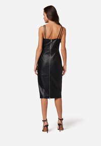 Schwarzes Leder-Midi-Kleid mit dünnen Trägern und einem Reißverschluss in der Mitte des Rückens. Elegantes, figurbetontes Design mit glatter Textur und minimalistischem Detail.