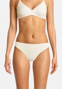 Reggiseno bianco senza cuciture e mutandine bikini abbinate, caratterizzati da una texture liscia, copertura minima e bande larghe per una vestibilità comoda.