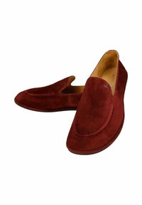 Scarpe slip-on in suede rosso con punta rotonda, cuciture decorative e un piccolo emblema vicino all'apertura. Fodera interna liscia.