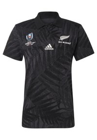 Svart polo-shirt med ett mönster av ormbunkar, med "ALL BLACKS"-logotypen och Rugby World Cup-emblemet. Tillverkad av andningsbart tyg med krage.