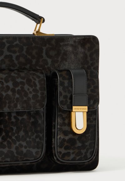 Sac à main en fausse fourrure à imprimé léopard noir avec des accents en cuir, présentant une forme structurée, des détails en or et deux poches avant.