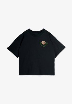 Juodas medvilnės marškinėlis su apvaliu kaklu ir trumpomis rankovėmis, papuoštas siuvinėtai veido ir lapų dizainu krūtinėje.