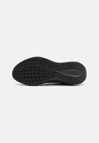 Semelle de chaussure en caoutchouc noir avec motif de bande de roulement en forme de losange et logo Nike au centre, vue de dessous sur fond blanc.