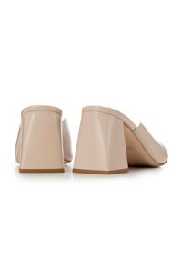 Mule beige con tacco, realizzate in pelle liscia, con una comoda apertura posteriore ampia e tacchi a blocco geometrici. La texture è elegante con una leggera lucentezza.
